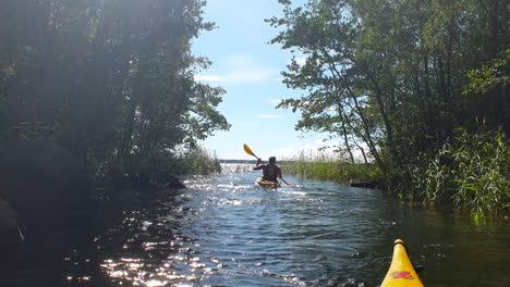 guy kayaking in narrow river, summer adventure, pov from kayak