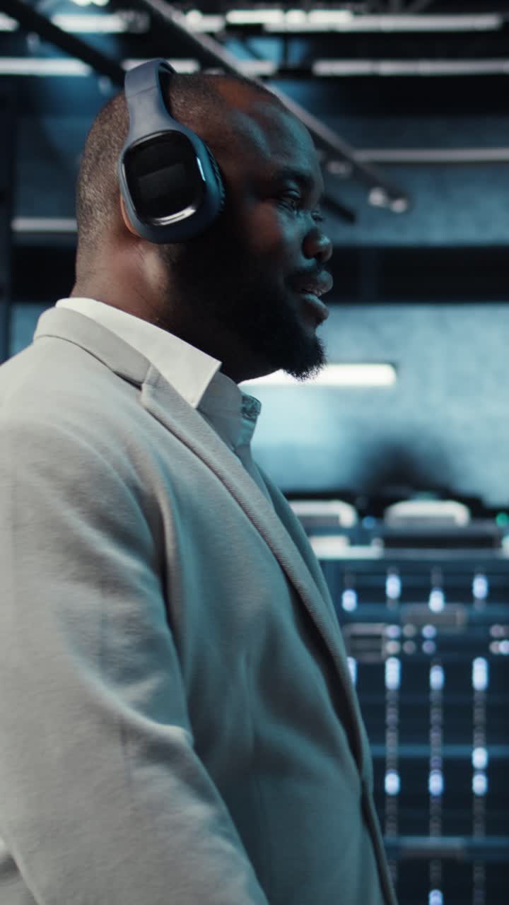 Vertical video Happy worker wearing headphones walking in data center