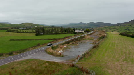 Forwards-tracking-of-black-car-driving-on-road-around-large-house-in-countryside-on-cloudy-day.--Ireland