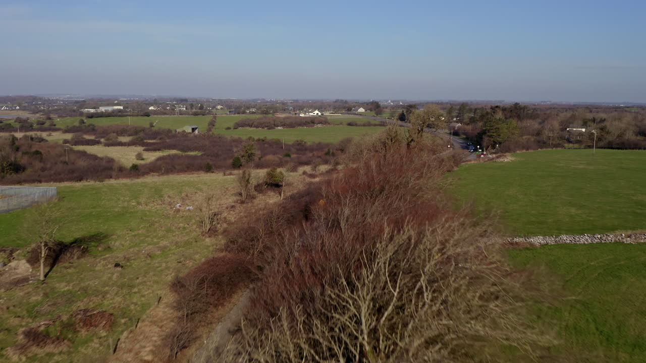 Aerial pullback over N67 Clarinbridge road on a sunny morning, revealing light traffic and water tower