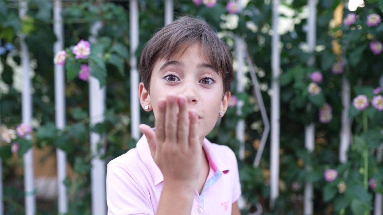 Niña de ocho años sonriendo y lanzando un beso al aire libre