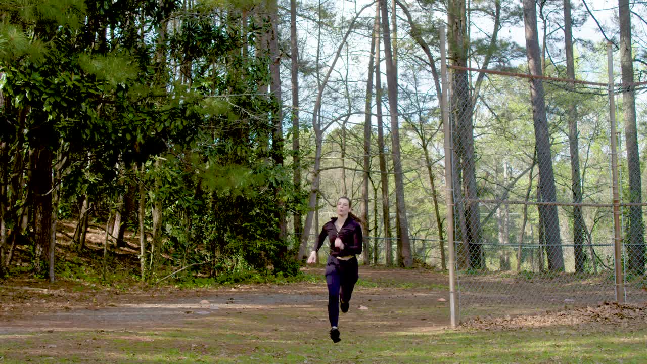 una mujer atlética se quema a través de una esquina y sigue corriendo mientras corre a través de un parque boscoso en atlanta, georgia para la aptitud y el ejercicio