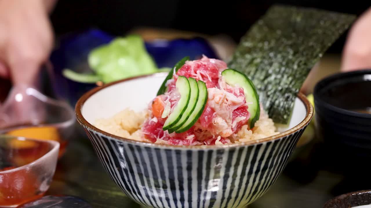 Close-up shot of a Japanese crab meat rice bowl with cucumber and seaweed garnish