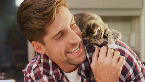 un joven sonriente jugando con su gato mascota en la cocina 4k 4k