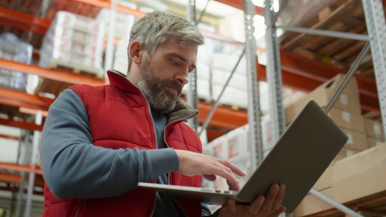 Warehouse worker uses laptop to check inventory