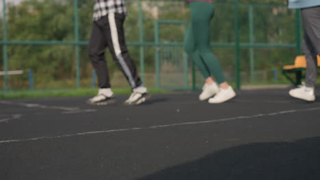 three leg view of two women jogging, one in green joggers and another in ash joggers with white sneakers, with a blurred background of a bar fence and people seated outdoors