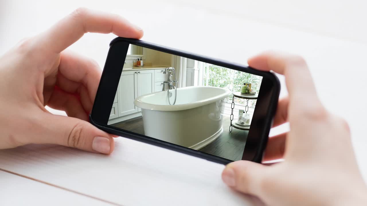 persona que sostiene un teléfono inteligente con interiores de baño modernos mostrados en la pantalla
