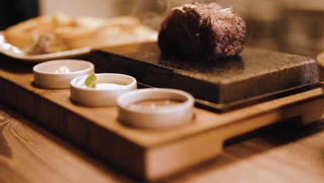 grilled steak on hot cooking stone, smoke, sauces, cinematic slow motion shot