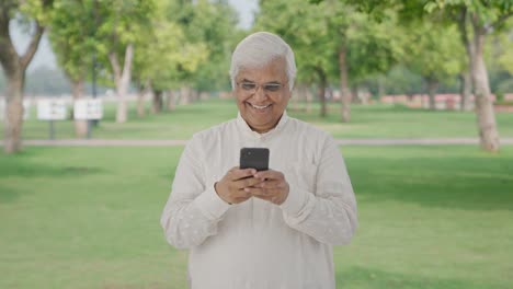 Happy-Indian-old-man-chatting-on-phone-in-park