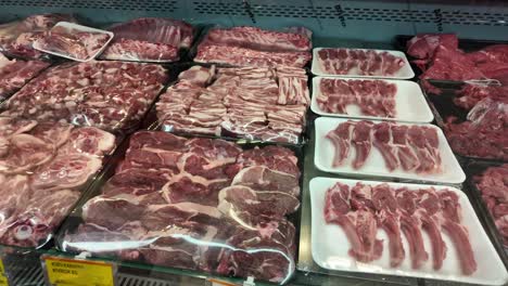 various cuts of raw meat on display at a grocery store