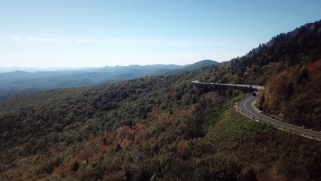 Vista-Aérea-Otoñal-Del-Viaducto-De-Linn-Cove-Con-La-Montaña-Hawksbill-Y-Table-Rock-A-Lo-Lejos