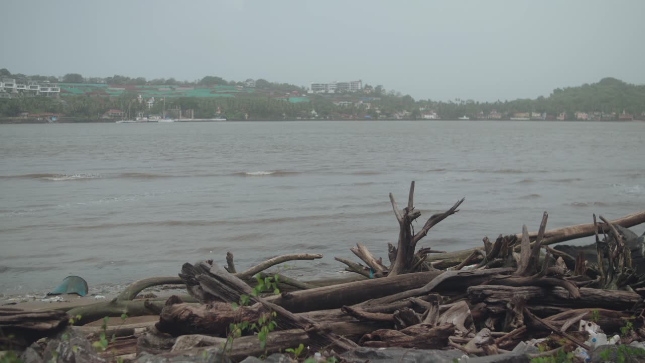 Gentle waves lap against a wooden shore beneath misty grey clouds in calm weather