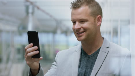 Hombre-De-Negocios-Teniendo-Video-Chat-Usando-Un-Teléfono-Inteligente-Chateando-En-Un-Vendedor-De-Teléfonos-Móviles-Disfrutando-De-Una-Conversación-Con-Un-Cliente-En-El-Lugar-De-Trabajo-De-La-Oficina-Corporativa-4k