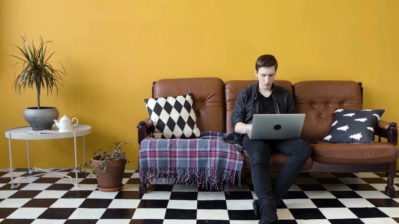 hombre trabajando en una computadora portátil en un sofá