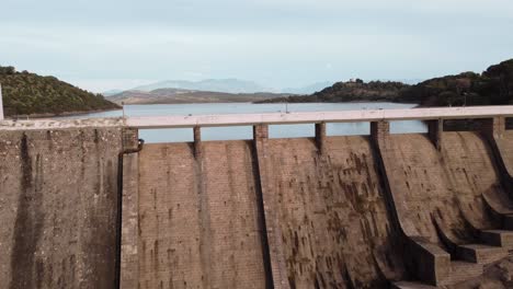 Establisher-aerial-of-Dam,-drone-flying-above-road-reveal-amazing-lake-landscape