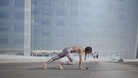 woman standing in warrior pose at street. girl practicing yoga on city street