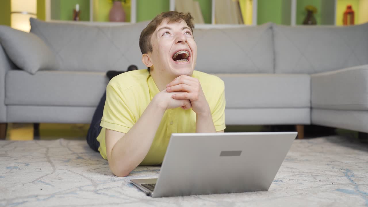 joven viendo videos divertidos en su computadora portátil en casa.