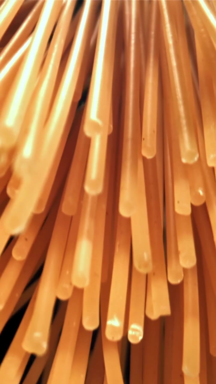 Fili di spaghetti crudi che si sollevano su sfondo nero
