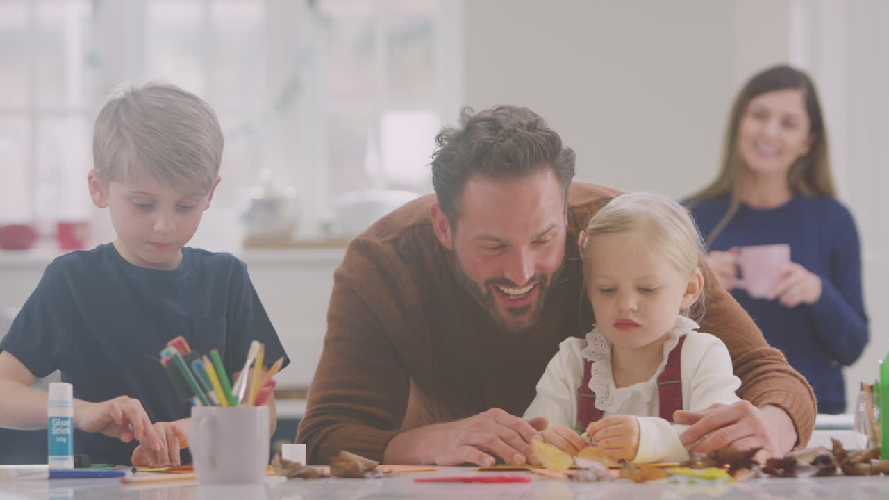 Famiglia a casa che fa lavoretti e crea un quadro con foglie in cucina