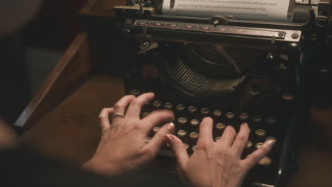 toma cinematográfica sobre el hombro de una mujer escribiendo en una máquina de escribir antigua