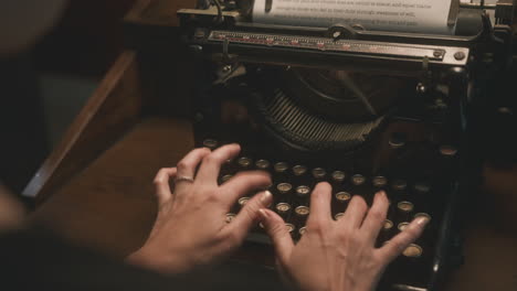 cinematic over the shoulder shot of woman typing on vintage typewriter