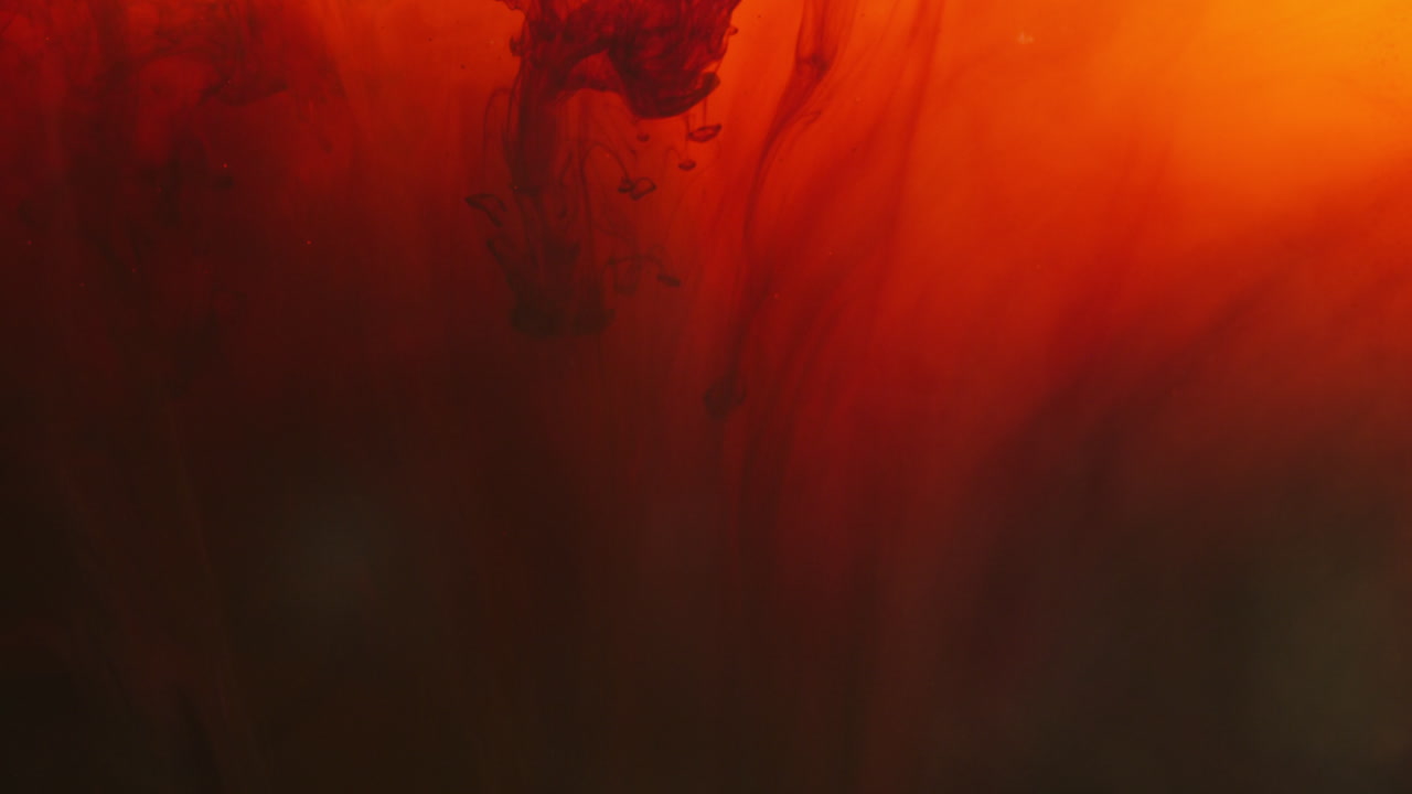 빨간색과 검은색 페인트 또는 염료가 색 바탕에 물에 떨어지면 회전하는 다채로운 연기 바탕을 만니다.