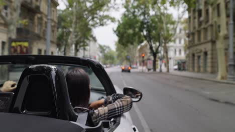 mujer conduciendo un descapotable en la ciudad