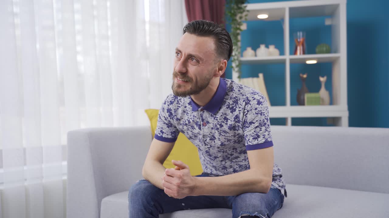 hombre sentado en el sofá en casa feliz y soñando despierto, soñando, deseando bien.