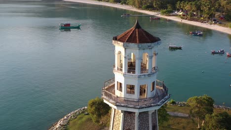 cinematic orbiting shot drone fly around tourist landmark perdana quay light house with fishing boats moored on the gulf, beautiful scenery at langkawi island, kedah, malaysia, southeast asia