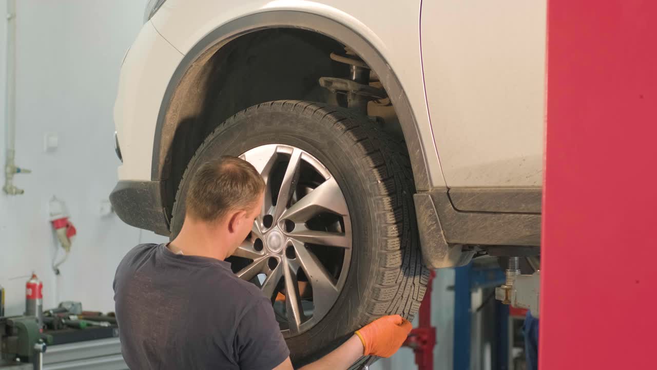 manos del mecánico con la herramienta, cambiando el neumático del coche en el servicio de automóviles