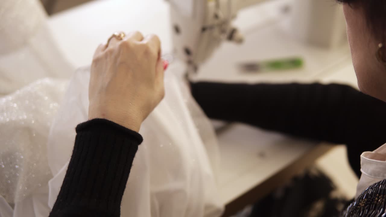vista de ángulo alto de la máquina de coser, costura de hilo de punto. equipo para coser vestido de novia elegante. sastre femenina trabajando a mano