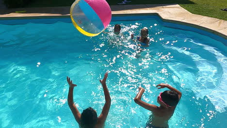 children playing ball game in swimming pool on hot summer day.