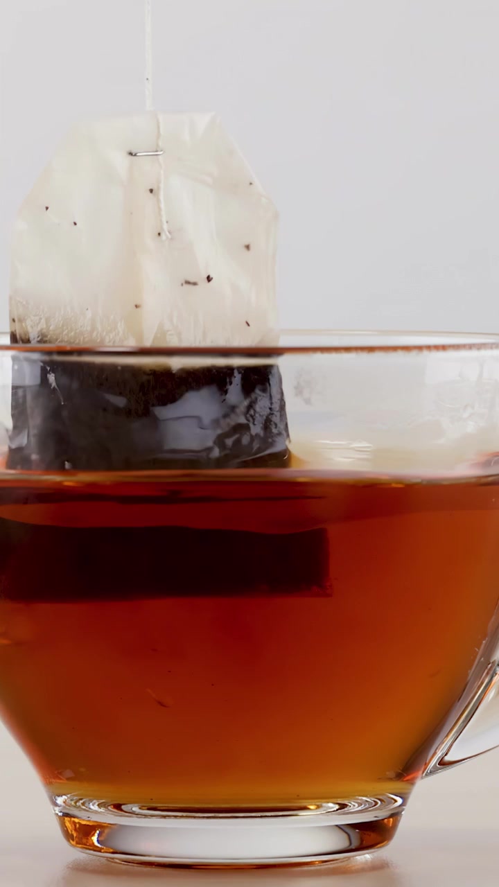 Bustina di tè in infusione in una tazza di vetro trasparente