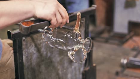 glass artist skillfully shapes curved handle on a vase he is creating