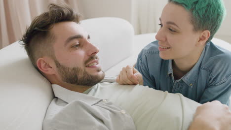 Pareja-Joven-Tumbada-En-El-Sofá-Hablando-Y-Acariciándose