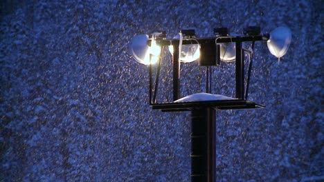 snow falls at night through beaming floodlights