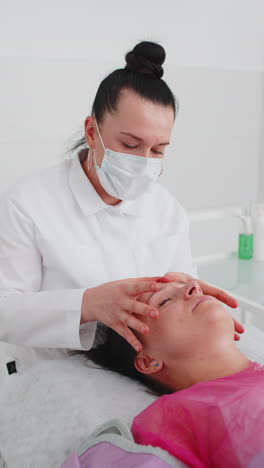terapeuta de cosmetología haciendo mujer relajante spa masaje facial con las manos en el salón de desintoxicación y curación