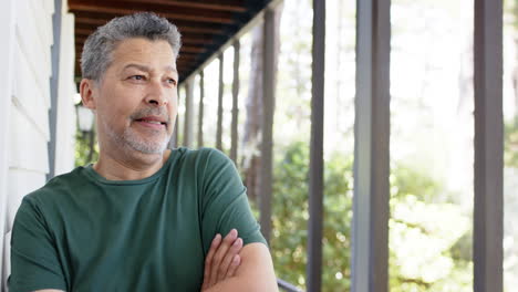 Retrato-De-Un-Hombre-Mayor-Birracial-Feliz-Con-Los-Brazos-Cruzados-En-El-Soleado-Exterior,-Espacio-Para-Copiar