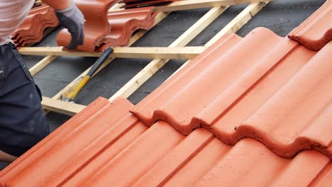 techador profesional instalando tejas de techo de hormigón rojo en una casa residencial