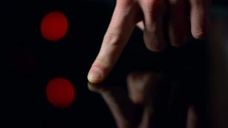 Macro-video-of-man-finger-touching-black-surface.-Accurate-male-finger-.