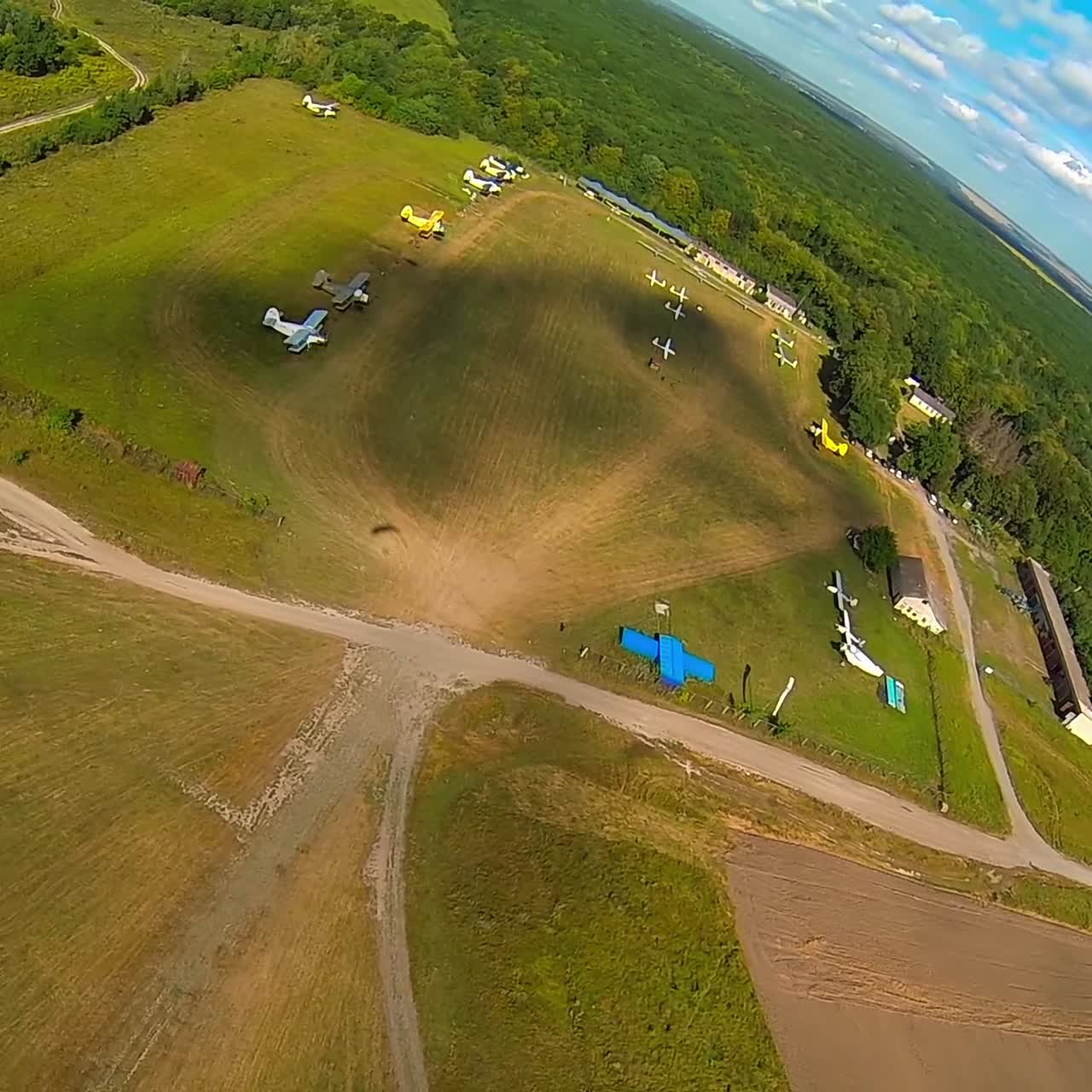 Under the cupola of black and orange parachute. Extreme sportsman descending to the land. Beautiful picturesque view under blue skies