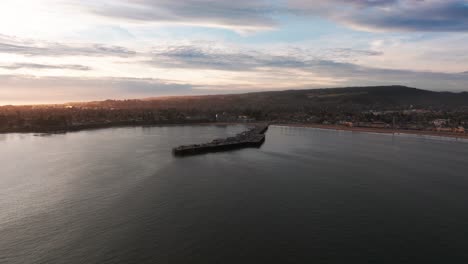 slow dramatic drone shot overlooking santa cruz pier and beach area sunset