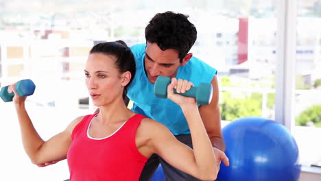 mujer en forma levantando pesas con entrenador