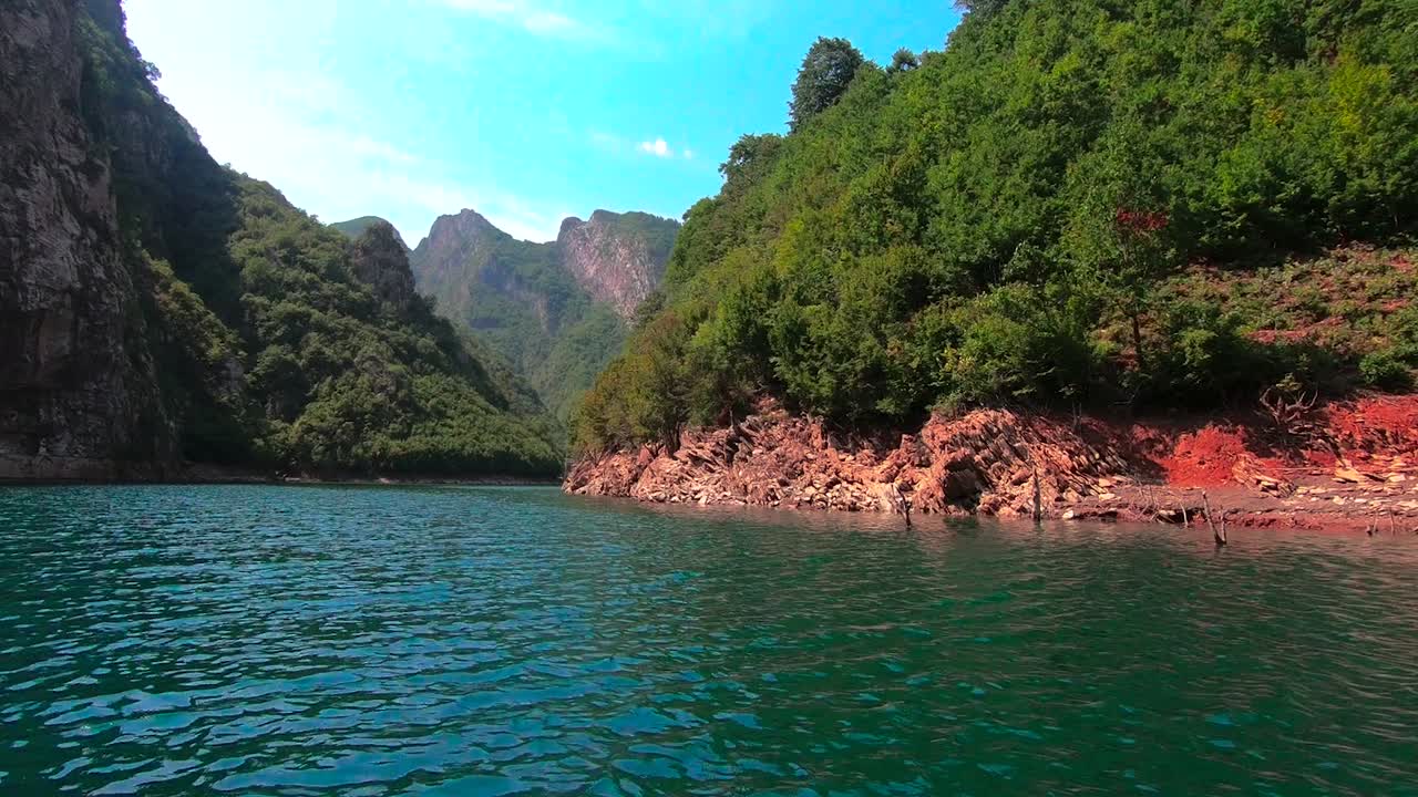 Colorful valley with river streaming across Alps mountains with lush vegetation and rocky slopes