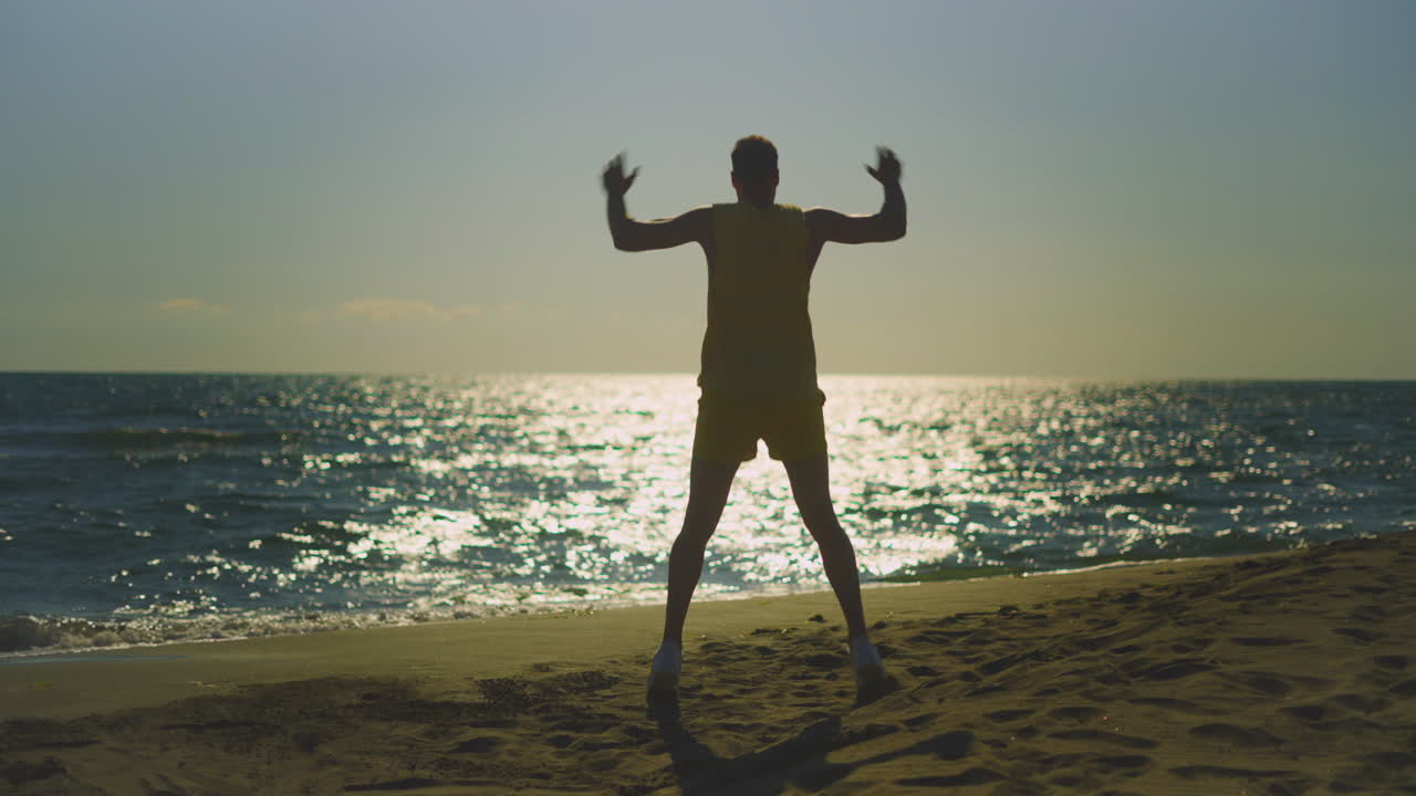 해가 지는 동안 해변에서 운동하는 남자