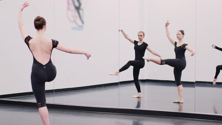 Female Students At Performing Arts School Rehearsing Ballet In Dance Studio Reflected In Mirror