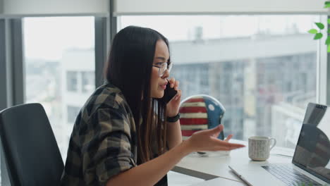 Gesturing-girl-explaining-cellphone-in-office-close-up.-Nervous-startuper-call