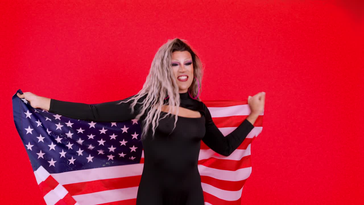 Drag Performer Wrapped in American Flag Against Red Background