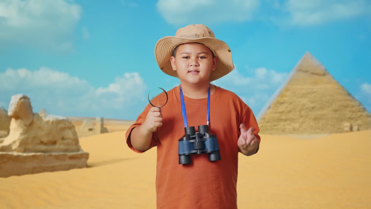 Asian Boy With A Hat And Binoculars Using The Magnifying Glass Then Showing Peace Gesture While Traveling In Giza Pyramid. Boy Researcher Examines Something, Travel Tourism Adventure Concept