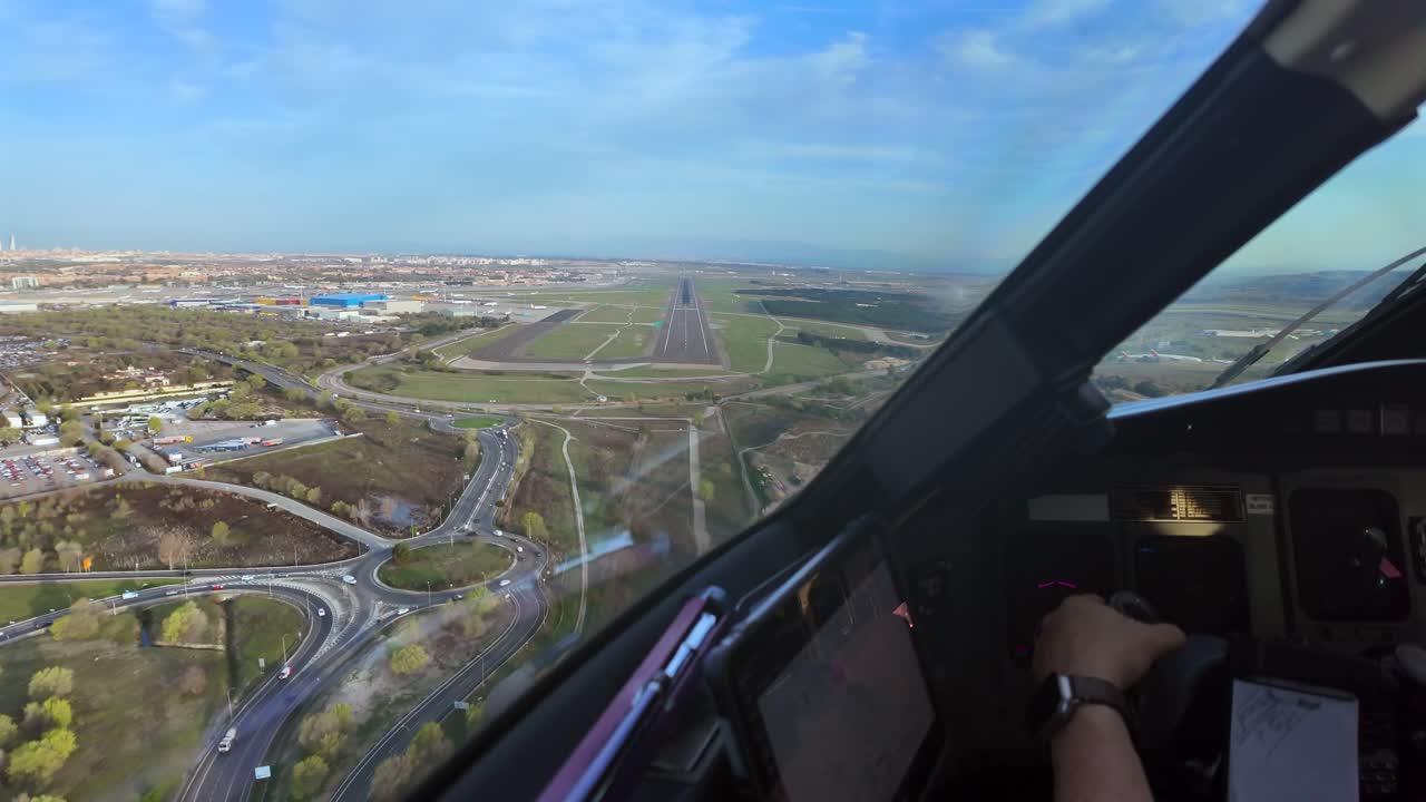 Prospettiva immersiva del pilota attraverso i finestrini della cabina di pilotaggio di un avvicinamento in tempo reale all'aeroporto di Madrid (MAD), con vista della mano del pilota che aziona i comandi di volo.